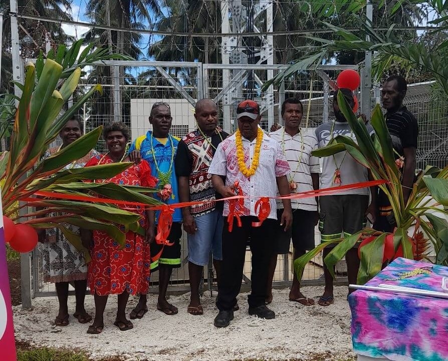 A group of Digicel staff cutting a ribbon in front of the new cell tower in Malo