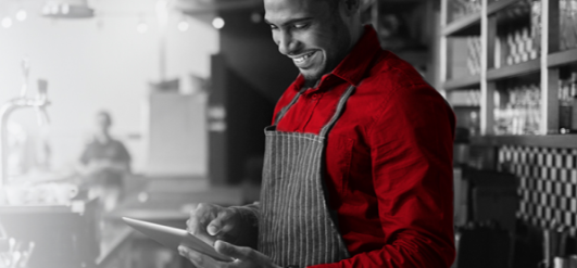 A barista smiling using a tablet