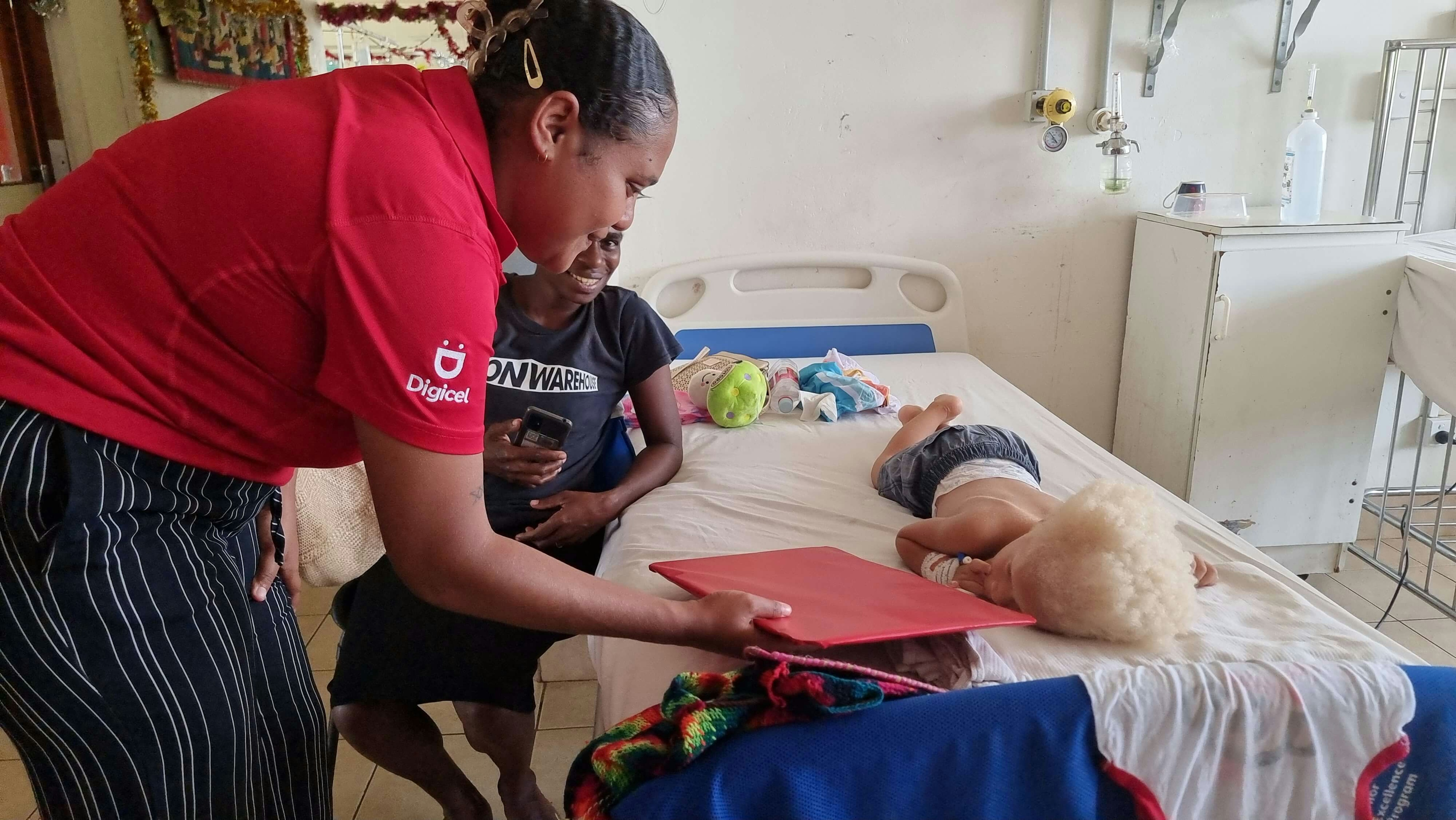 A Digicel employee handing a toy to a child at the Vila Central Hospital